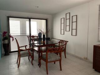 Dining area with wooden table and chairs, large windows, and decorative elements