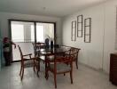 Dining area with wooden table and chairs, large windows, and decorative elements