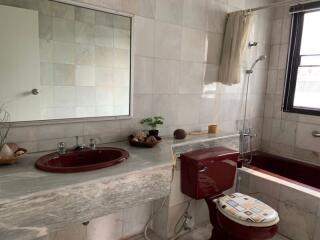 Bathroom with marble countertop, red fixtures, and large mirror