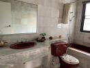 Bathroom with marble countertop, red fixtures, and large mirror