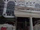 Exterior view of a multi-story residential building with intricate balcony designs and a 'For Rent' sign