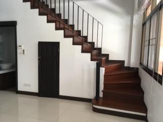 Modern wooden staircase with under-stairs storage and nearby sink area