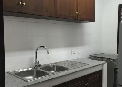 Simple kitchen with wooden cabinets and steel sink