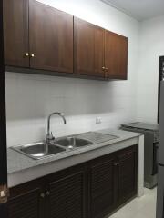 Simple kitchen with wooden cabinets and steel sink