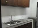 Simple kitchen with wooden cabinets and steel sink