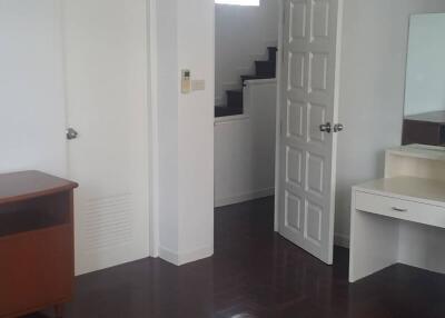 Bedroom with white walls, open door and dark-wood floor