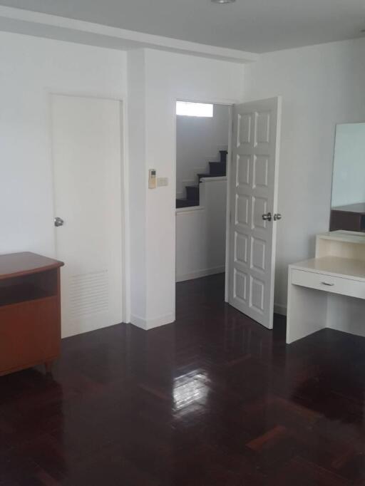 Bedroom with white walls, open door and dark-wood floor