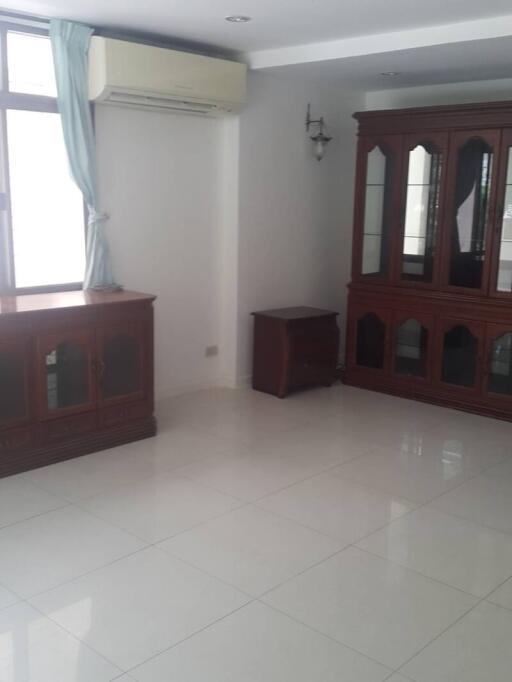 Living room with large window, air conditioner, and wooden furniture