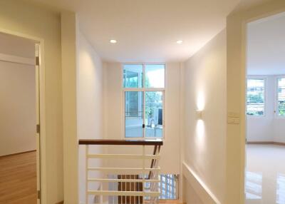 Well-lit hallway with stairway and open rooms