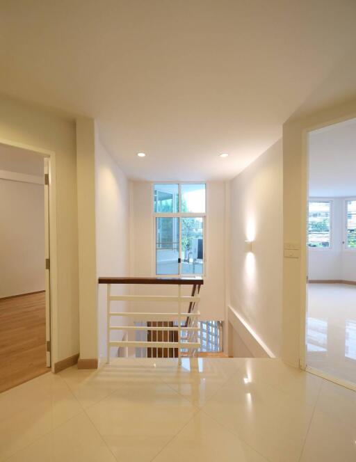 Well-lit hallway with stairway and open rooms