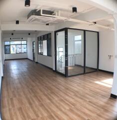 Spacious office area with large windows and wooden flooring