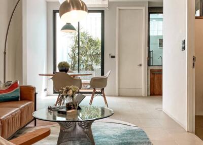 Modern living room with glass table, stylish rug, and adjacent dining area.