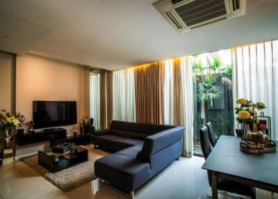 Modern living room with large windows, plants, and a dining area