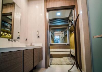 Modern bathroom with a large sink, mirror, and a view of a walk-in closet area.