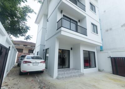 Exterior view of a three-story residential building with a balcony and parked car