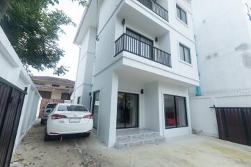 Exterior view of a three-story residential building with a balcony and parked car