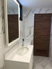 Modern bathroom with marble walls and wooden door