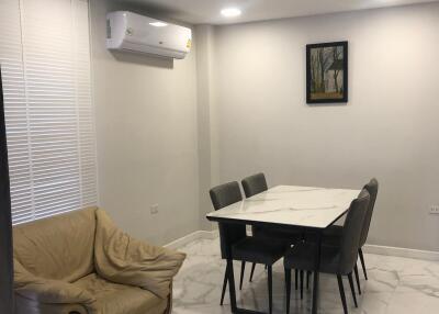 Modern dining area with table, chairs, beige armchair, and air conditioner