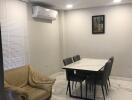 Modern dining area with table, chairs, beige armchair, and air conditioner