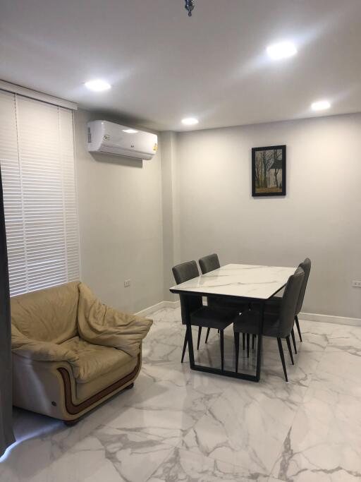 Modern dining area with table, chairs, beige armchair, and air conditioner