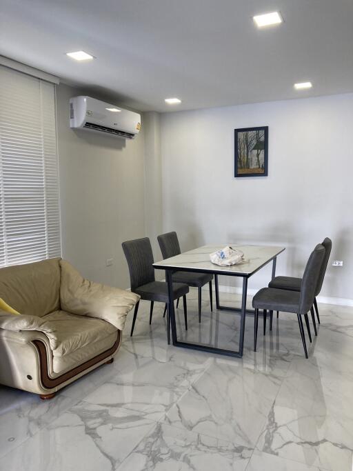 Modern living area with couch, dining table, and wall-mounted air conditioner.