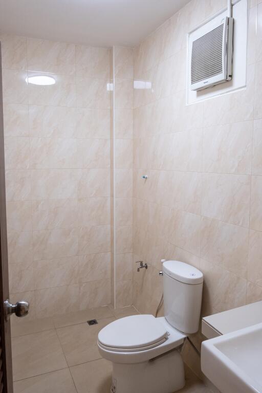 Tile bathroom with toilet, sink, and ventilation fan