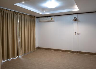 Living room with tiled floor, recessed ceiling lights, split air-conditioning unit, and beige curtains