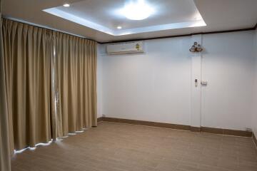 Living room with tiled floor, recessed ceiling lights, split air-conditioning unit, and beige curtains