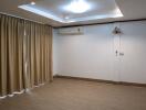 Living room with tiled floor, recessed ceiling lights, split air-conditioning unit, and beige curtains