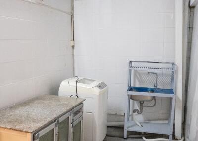 Laundry room with washing machine, sink, and storage cabinet