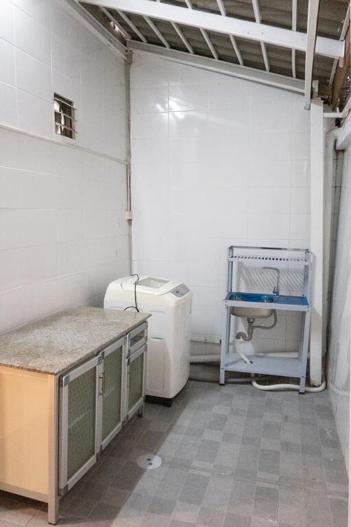 Laundry room with washing machine, sink, and storage cabinet