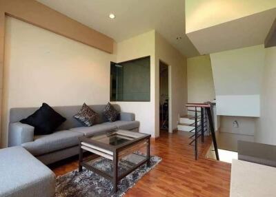 Modern living room with sofa, glass coffee table, and wooden flooring