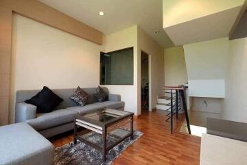 Modern living room with sofa, glass coffee table, and wooden flooring