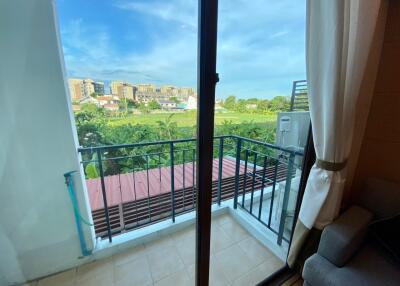 View of a balcony with railing, overlooking a green landscape and buildings in the distance