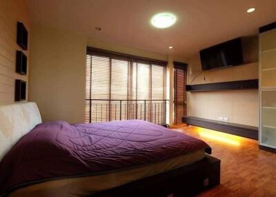 Spacious bedroom with large window, modern furnishings, and ample lighting