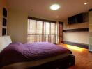 Spacious bedroom with large window, modern furnishings, and ample lighting