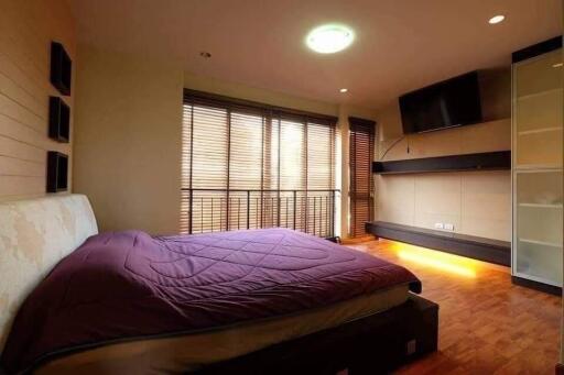 Spacious bedroom with large window, modern furnishings, and ample lighting