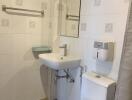 Small, white-tiled bathroom with sink, toilet, mirror, and towel rack