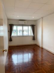 Empty bedroom with large window and wooden floor