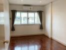 Empty bedroom with large window and wooden floor