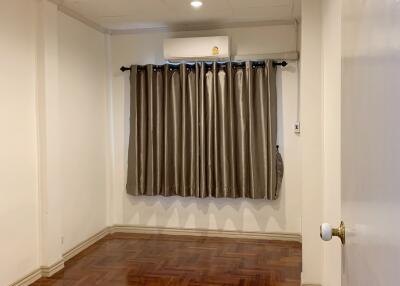 Empty bedroom with wooden flooring, ceiling lights, and curtains