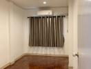 Empty bedroom with wooden flooring, ceiling lights, and curtains