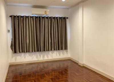 Empty bedroom with hardwood floors and window with curtains