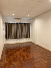 Empty bedroom with hardwood floors and window with curtains