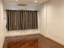 Empty bedroom with hardwood floors and window with curtains