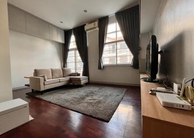 Modern living room with a sofa, TV, and large windows