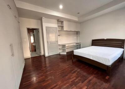 Spacious bedroom with wooden flooring, a bed, and built-in cabinetry.