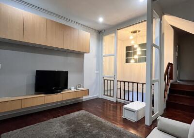 Modern living room with TV, beige sofa, and wooden cabinets