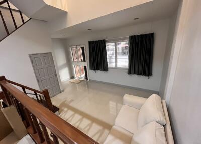 Modern living room with white sofa and large window with dark curtains.