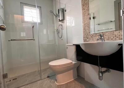 Modern bathroom with glass shower enclosure and wall-mounted sink.